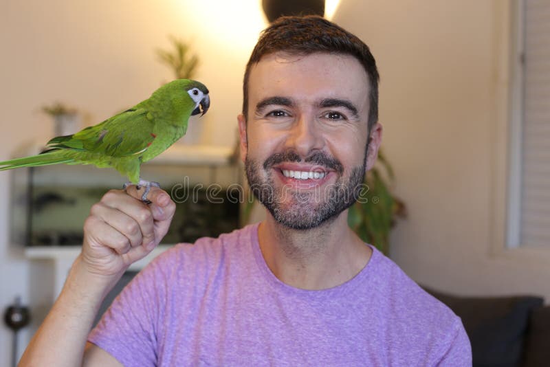 Man holding green dwarf macaw on finger. Man holding green dwarf macaw on finger.