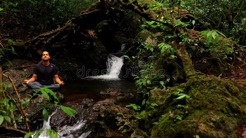 Man die mediteert op een waterval met een groene vlakke hoekclip in het lijsterbos