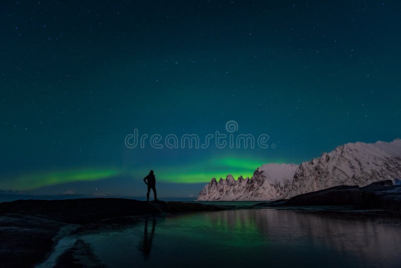 Man die naar de noordelijke lichten kijkt, Aurora Borealis, Devil Teeth Mountains in background, Tungeneset, Senja, Noorwegen royalty-vrije stock foto's Man die naar de noordelijke lichten kijkt, Aurora Borealis, Devil Teeth Mountains in background, Tungeneset, Senja, Noorwegen royalty-vrije stock foto's