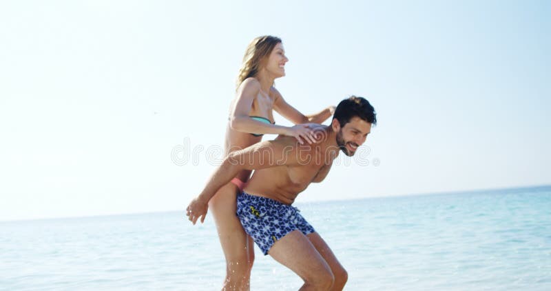 Man die op de rug rit geven aan vrouw bij strand