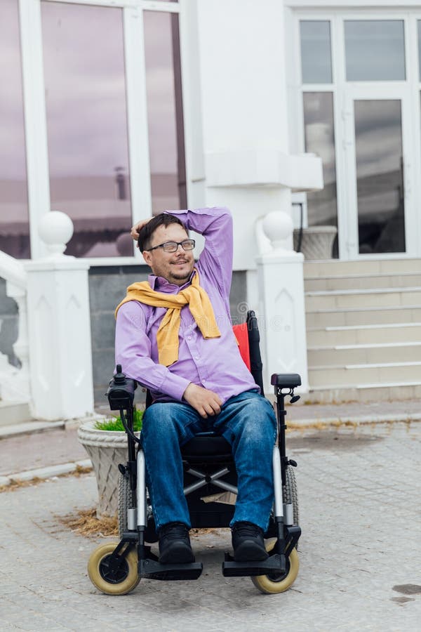 A Man with a Disability in a Wheelchair on a Walk on the Street Stock