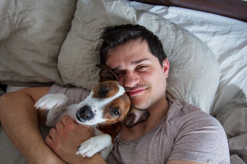 Man with dog lying down in the bed in a morning