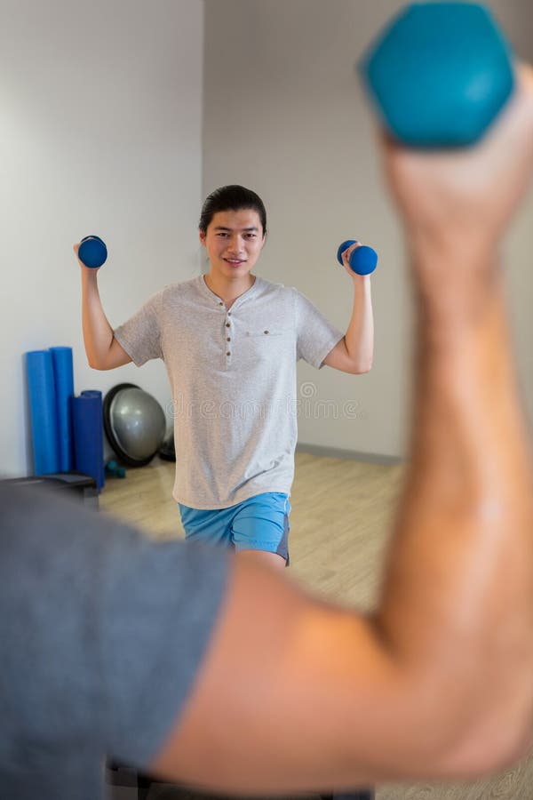 Two Men Doing Step Aerobic Exercise with Dumbbell on Stepper Stock