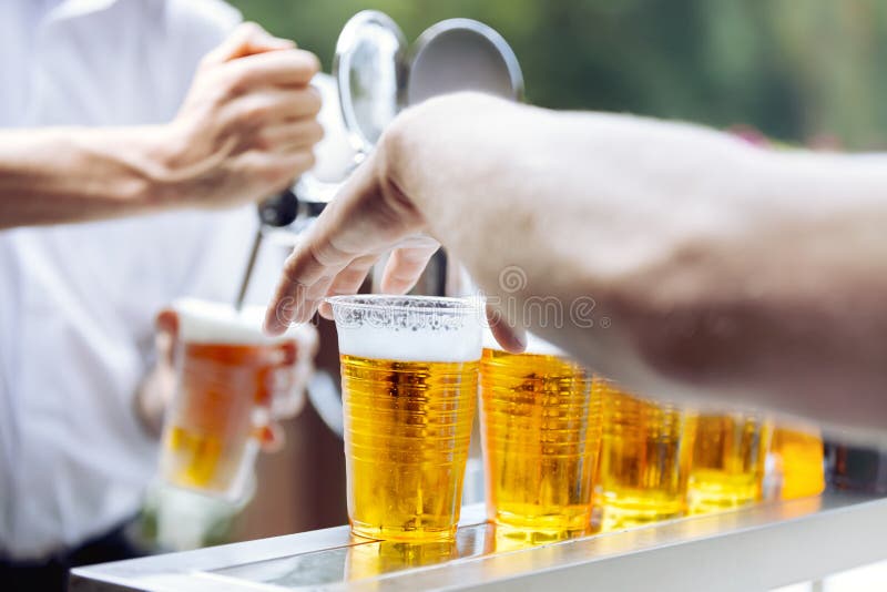 Man drawing beer. Hand takes beer plastic cup