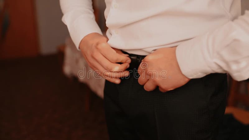 Man dressing in black suit fastening buttons white shirt jacket. man fastening belt in trousers.
