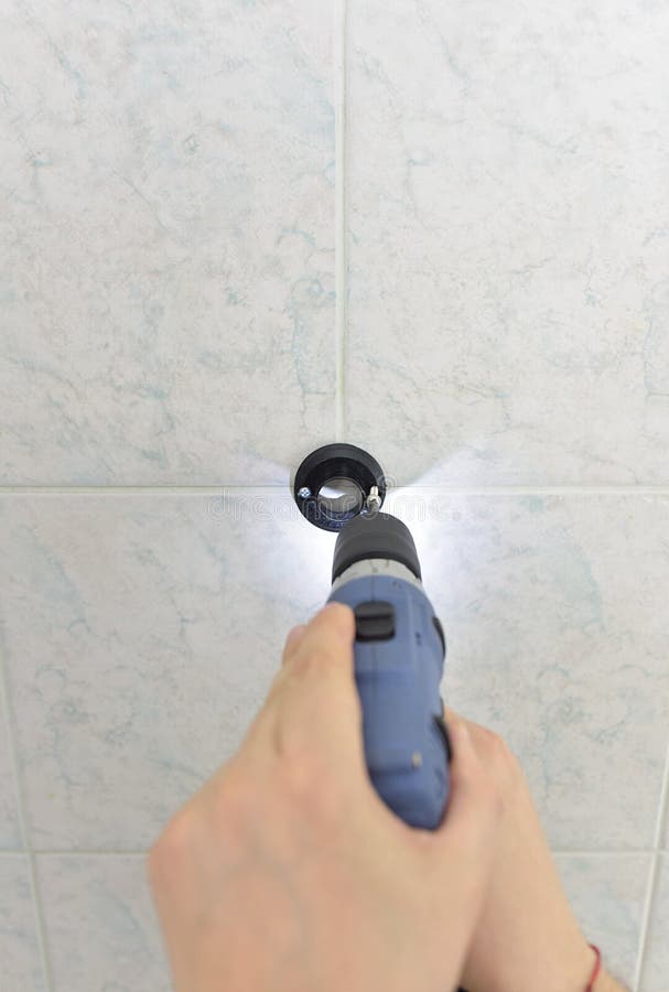 Man Drills with an Electric Drill into the Wall of Tiles in the