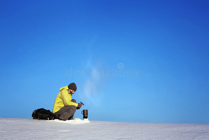 Man drinking hot coffee in thermos mug and looking into the mountains in snow, winter hike. Frost, landscape.