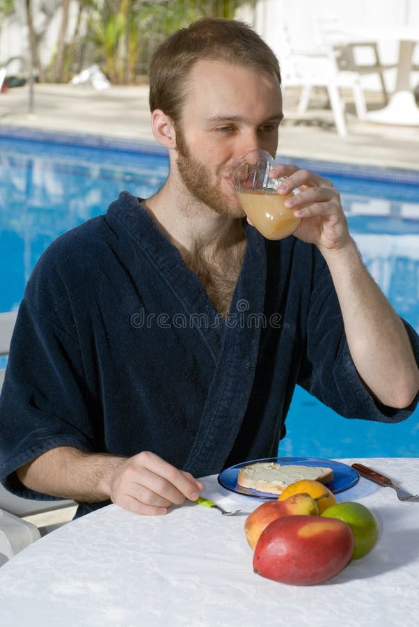 Man Drinking Juice Next to a Pool - Vertical