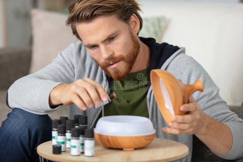 man drips essential oil into aromatherapy diffuser
