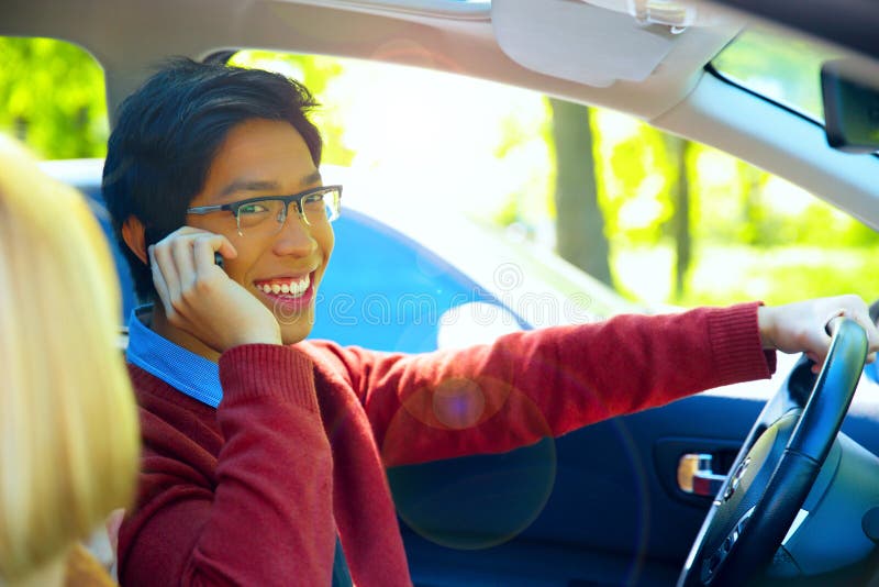 Young happy man driving car and speaking on mobile phone