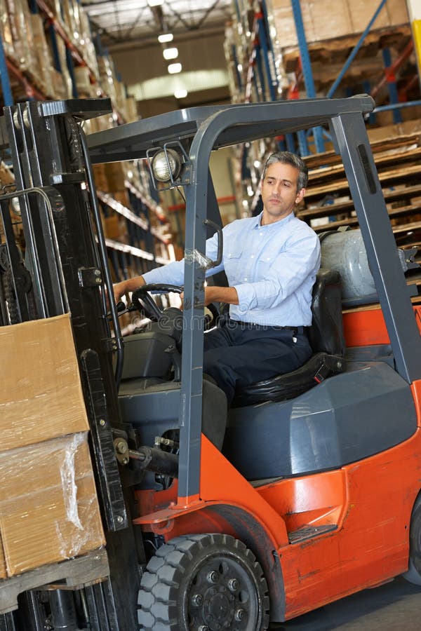 Man Driving Fork Lift Truck In Warehouse