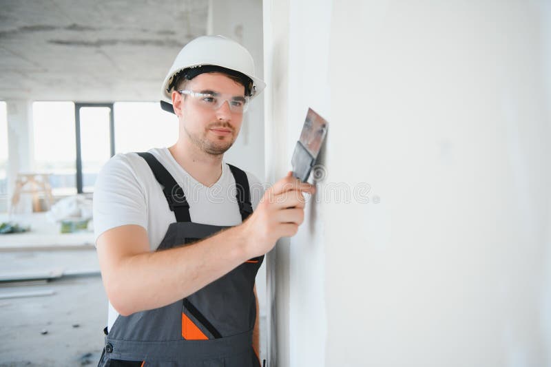 Man drywall worker using trowel for plasterer putting stucco on plasterboard white wall royalty free stock photo