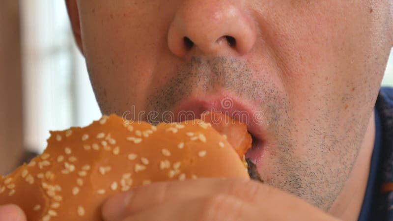 Man eating a hamburger. close-up shot. Fast food eats. Close up of man eating burger.