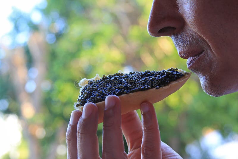 Man eating a sandwich with black caviar