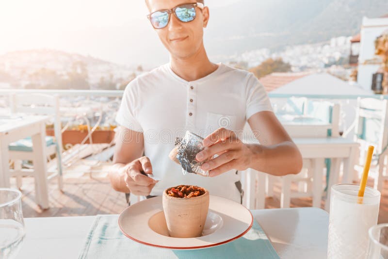 Man eating Testi kebab in restaurant on a terrace. It is an authentic Turkish delicious meat dish baked in a clay pot stock image