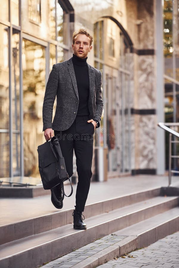 Man in elegant formal wear outside against modern building talking