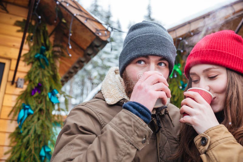 Handsome men and pretty young women drinking hot coffee on traditional christmas market. Handsome men and pretty young women drinking hot coffee on traditional christmas market