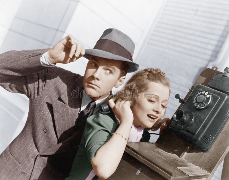 Man en vrouw die op een buitentelefoon luisteren (Alle afgeschilderde personen leven niet langer en geen landgoed bestaat Leveran royalty-vrije stock afbeelding Man en vrouw die op een buitentelefoon luisteren (Alle afgeschilderde personen leven niet langer en geen landgoed bestaat Leveran royalty-vrije stock afbeelding