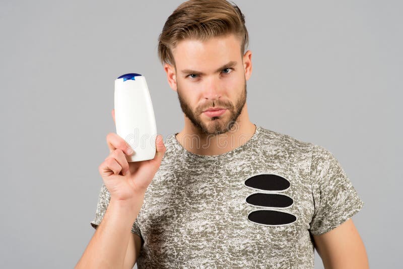 Man enjoy freshness after washing hair with shampoo. Guy with hairstyle holds bottle shampoo, copy space. Hair care and