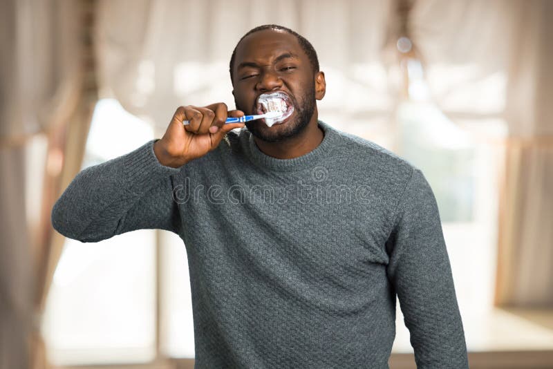 Man enthusiastically brushing teeth at home. - Stock Image - Everypixel