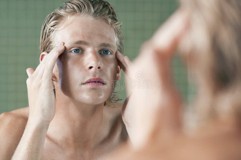 Man Examining Himself In Front Of Mirror