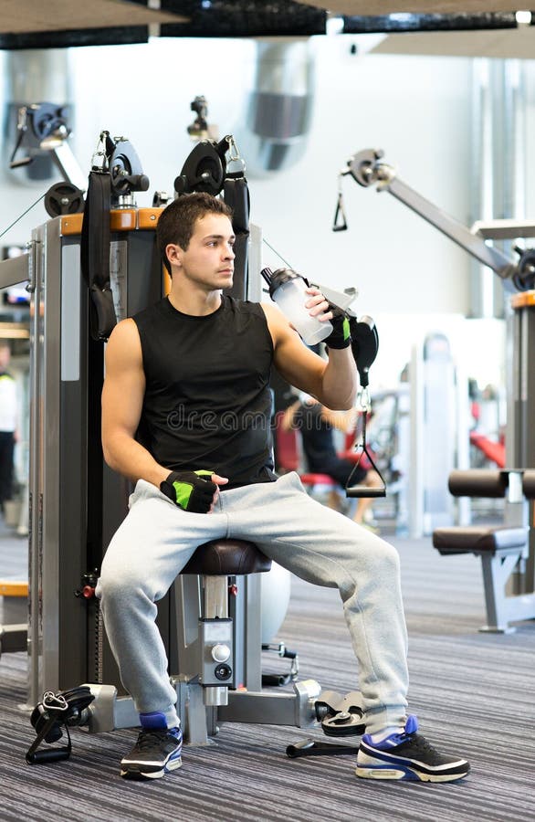 Sport, fitness, equipment, lifestyle and people concept - man exercising on gym machine