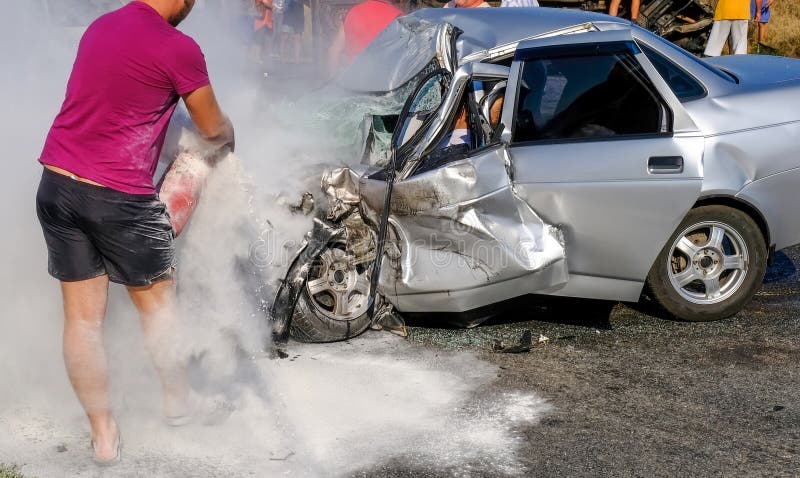 Man extinguishes the car with a fire extinguisher. Damaged vehicle closeup after car crash.