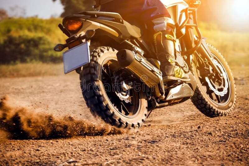 Man extreme riding touring enduro motorcycle on dirt field