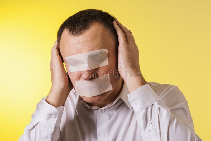 A man with eyes sealed with painting tape, a mouth and covering his ears with his hands against a yellow background