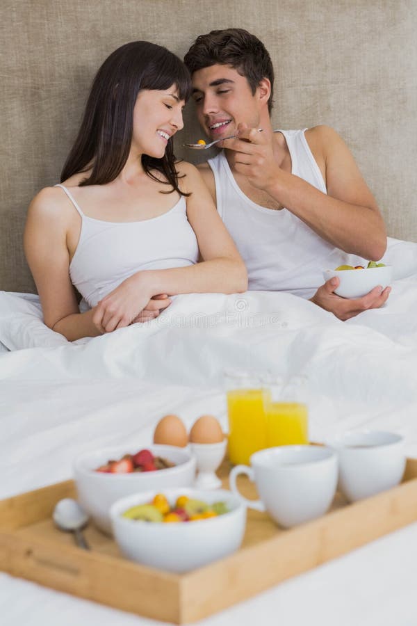 Man feeding breakfast cereals to women in bedroom. Man feeding breakfast cereals to women in bedroom