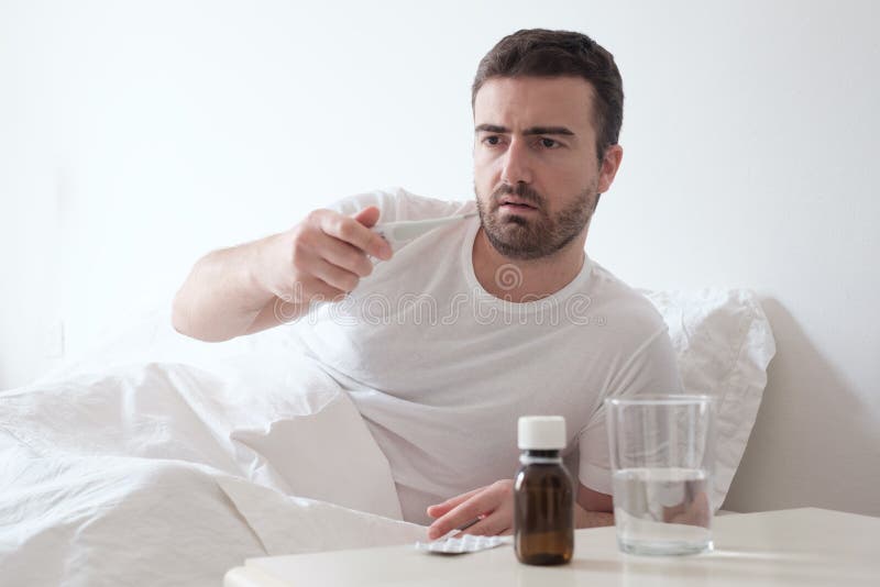 Man Feeling Bad Lying in the Bed and Looking the Thermometer Stock