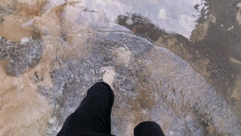 Man feet with hairy legs crossing cold mountain stream. Top view of male bare legs walking through cold river with stony bottom, concept of hiking. Man feet with hairy legs crossing cold mountain stream. Top view of male bare legs walking through cold river with stony bottom, concept of hiking.