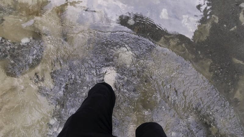 Man feet with hairy legs crossing cold mountain stream. Top view of male bare legs walking through cold river with stony bottom, concept of hiking. Man feet with hairy legs crossing cold mountain stream. Top view of male bare legs walking through cold river with stony bottom, concept of hiking.