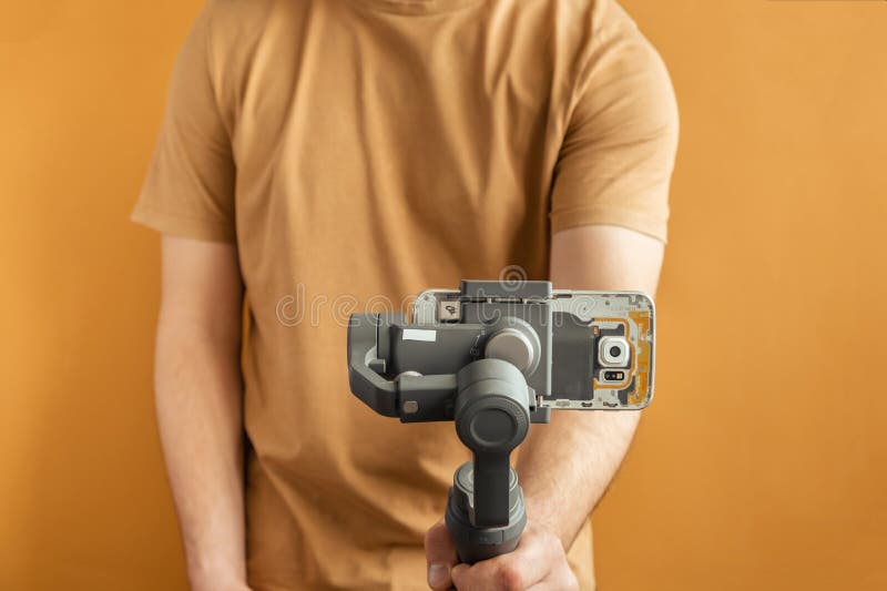 Man filming with a smartphone using a gimbal stabilizer on yellow background. Using three-axis electronic stabilizer to make vlogs stock photos