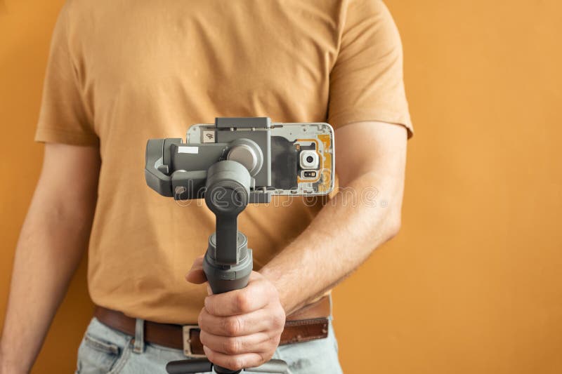 Man filming with a smartphone using a gimbal stabilizer on yellow background. Using three-axis electronic stabilizer to make vlogs stock photos