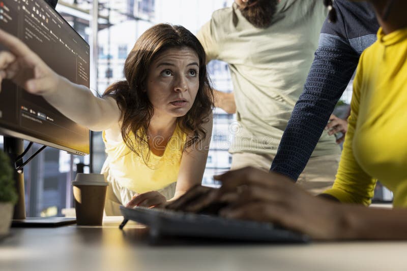 Man fixing coding mistakes assisted by colleagues doing brainstorming stock photography