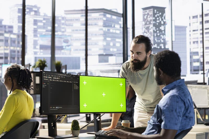 Man fixing coding mistakes on mockup computer, being assisted by colleague stock photo