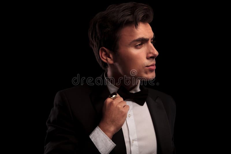 Man fixing his bow tie and looks to side