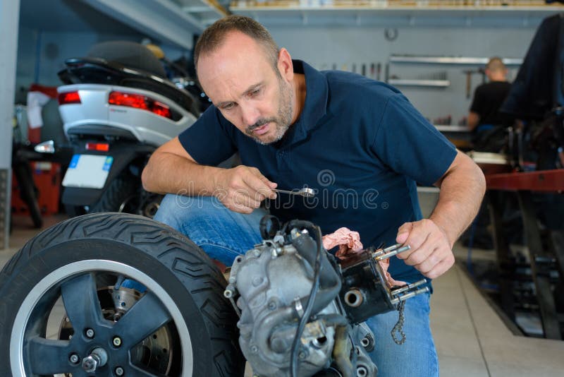 Man fixing motorcycle in garage stock image Man fixing motorcycle in garage stock image