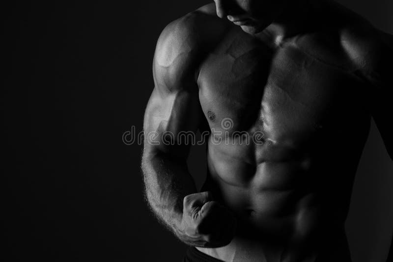 Close up of male muscular man flexing biceps muscle. Black and white studio shot on black background. Close up of male muscular man flexing biceps muscle. Black and white studio shot on black background.