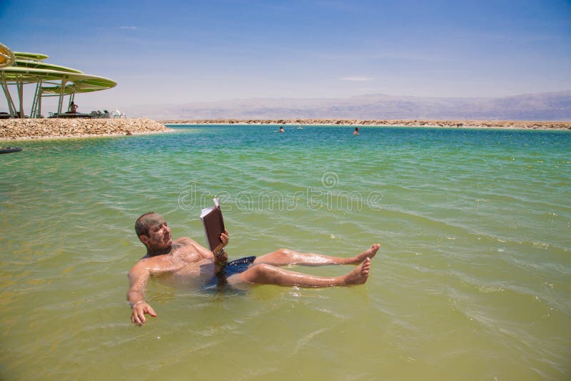 Man floating and reads a book at the Dead Sea