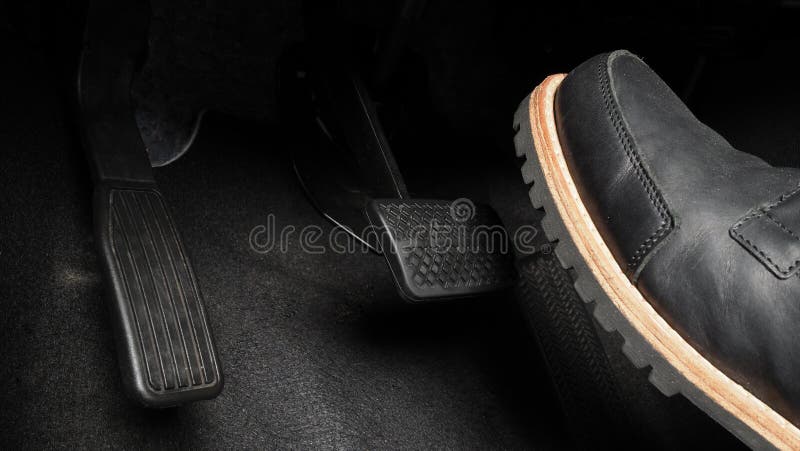 Man foot and accelerator and brake pedal inside the car