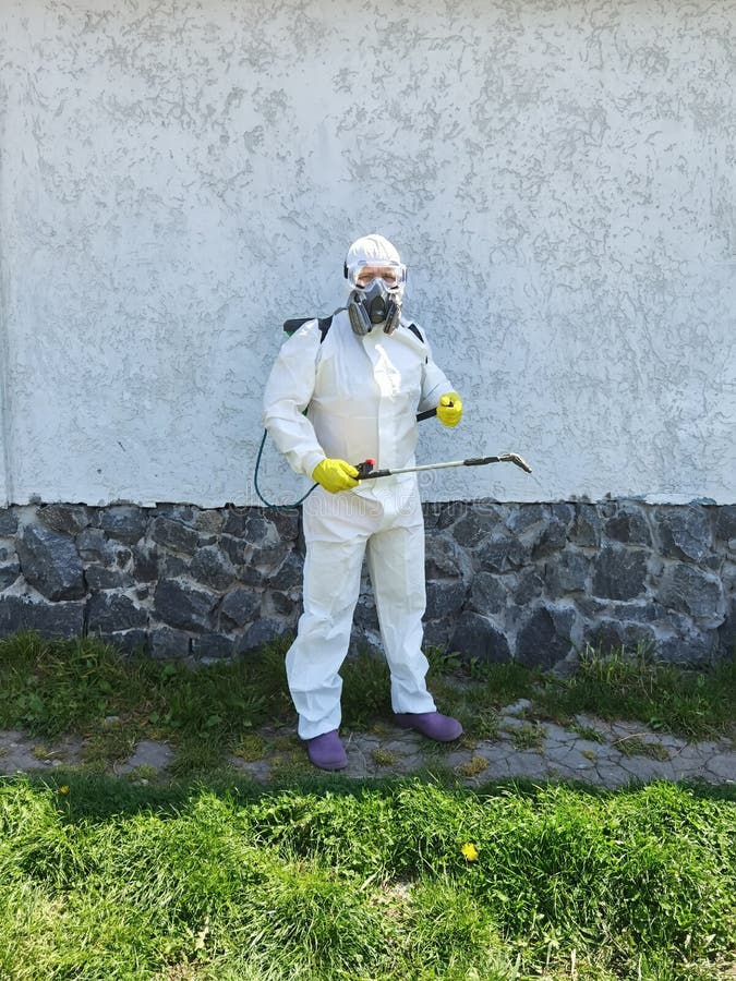 Man in Full Protective Clothing Using Pressure Washer. Stock Photo