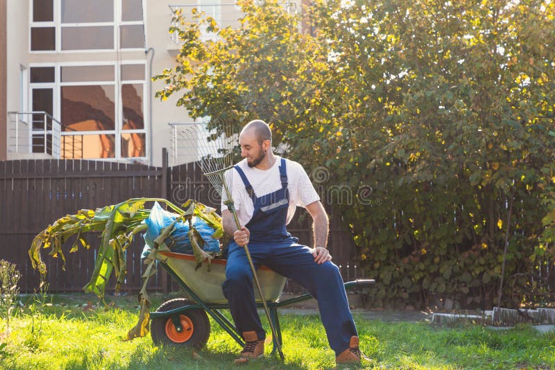Man-gardener resting after cleaning the yard. Smile and relax after work. Gardening and cleaning stock photos Man-gardener resting after cleaning the yard. Smile and relax after work. Gardening and cleaning stock photos