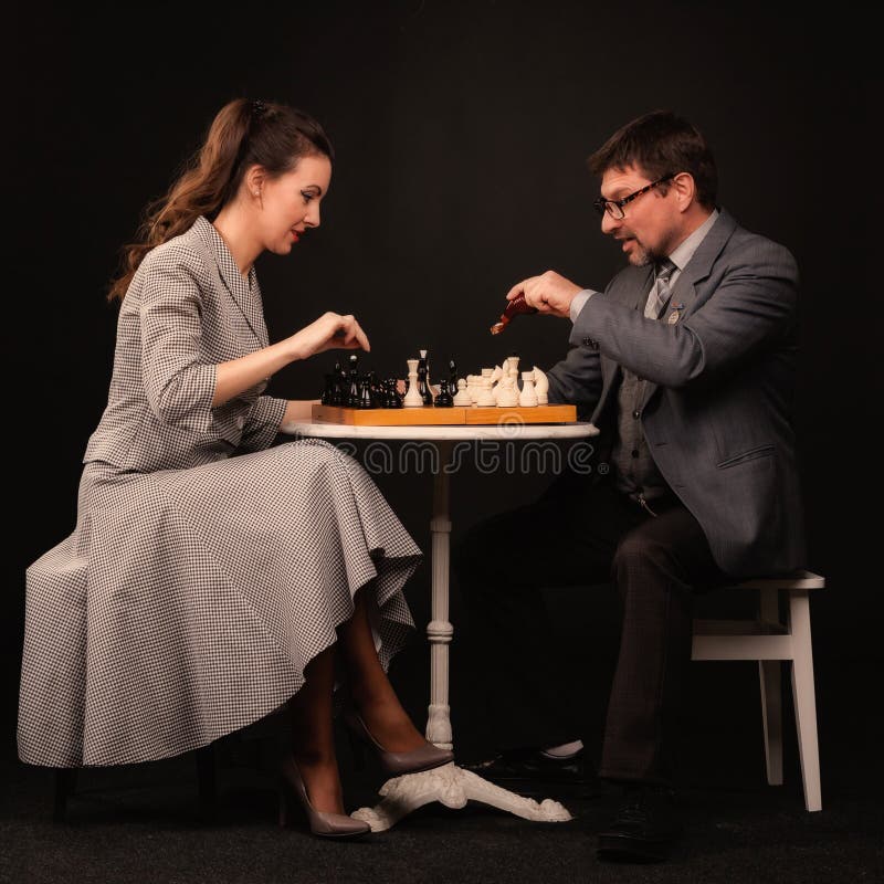 A man with a girl plays chess and smokes a pipe on a dark background royalty free stock photos A man with a girl plays chess and smokes a pipe on a dark background royalty free stock photos