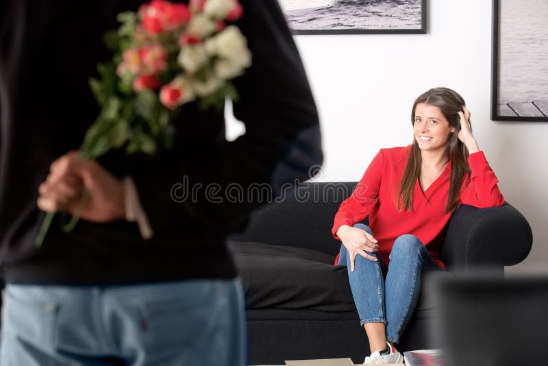 Man holding flowers behind his back to surprise his girlfriend. Man holding flowers behind his back to surprise his girlfriend