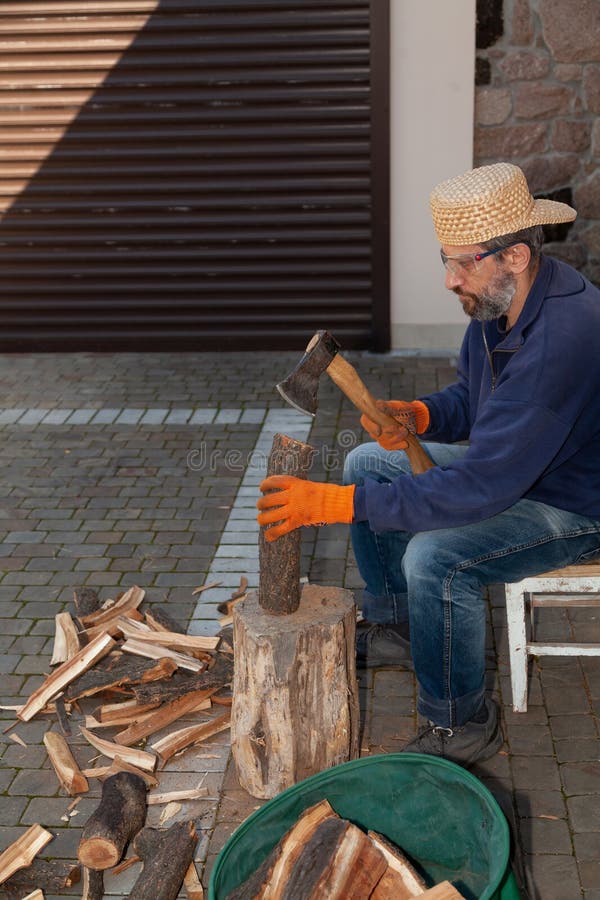 Man with glasses chopping wood in courtyard of house royalty free stock image
