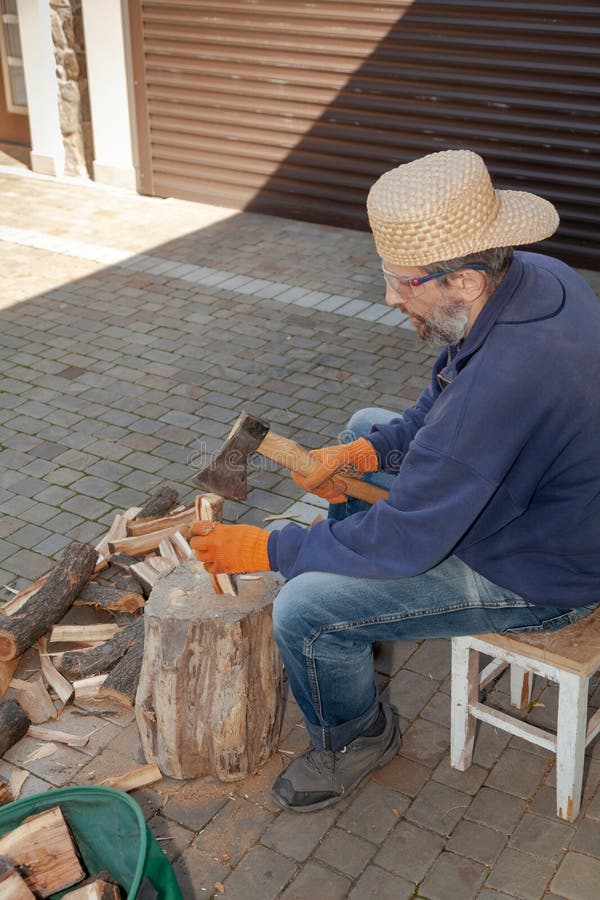 Man with glasses chopping wood in courtyard of house stock images