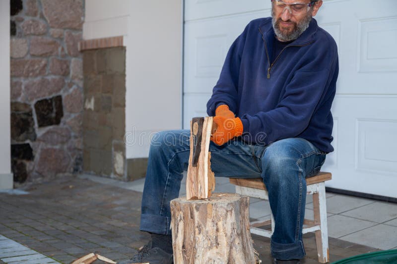 Man with glasses chopping wood in courtyard of house royalty free stock photos