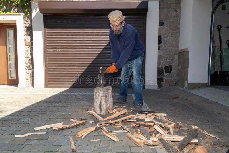 Man with glasses chopping wood in front of garage door royalty free stock photos